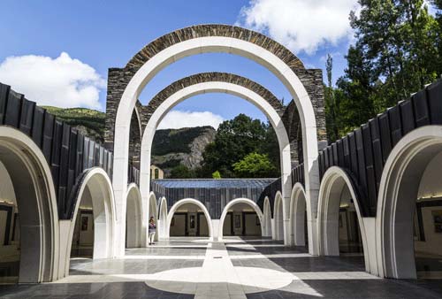 Patio abierto con grandes arcos blancos en el Santuario de Meritxell